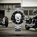 L'Orologio con teschio 3D Silver black di PACOSHOP presenta un audace teschio bianco su un quadrante nero con cinturino in acciaio inossidabile color argento, raffigurato all'aperto tra due motociclette nere e di fronte a un edificio industriale grigio.
