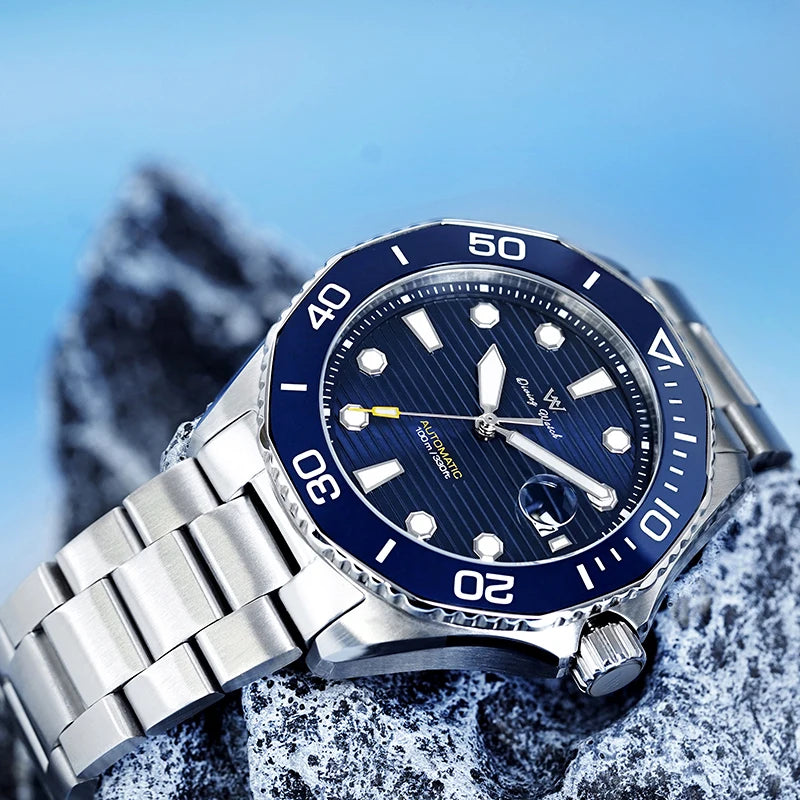 L'Orologio Automatico Acciaio Inossidabile vetro Zaffiro di PACOSHOP24.COM vanta una lunetta e un quadrante blu, indici bianchi e lancette argentate. Su una roccia grigia, mostra un'eleganza sportiva con il suo vetro zaffiro e la funzione di data sullo sfondo blu.