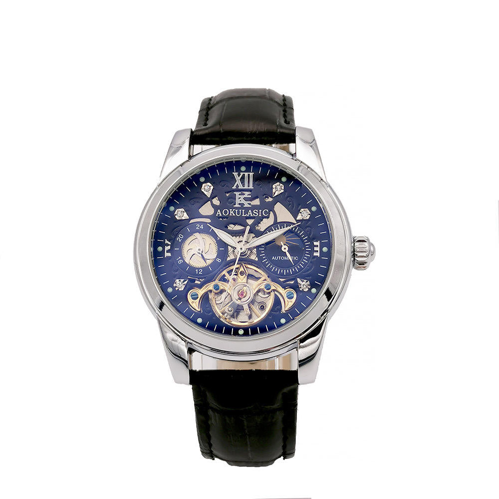 Il PACOSHOP24.COM Orologio automatico uomo con fasi lunari è dotato di cinturino in pelle nera, cassa argentata, intricato quadrante blu con molteplici contatori, numero romano XII, ingranaggi a vista e indicazione delle fasi lunari sul quadrante.