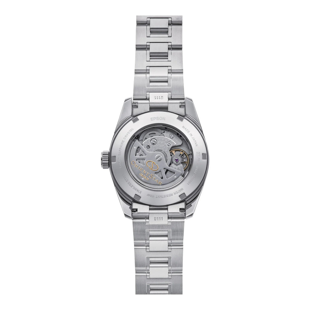 L'Orient Star Classic Automatico RE-AU0108G00B di Orient presenta un fondello aperto che rivela una meccanica precisa, maglie metalliche a vista, dettagli incisi e un quadrante arancione che spicca per un'eleganza vibrante dallo stile iconico.