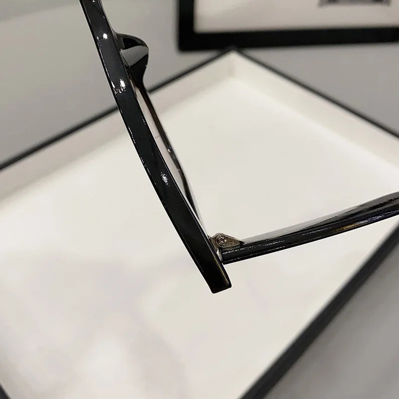 Primo piano della cerniera e del braccio laterale di PACOSHOP24.COM Occhiali da Sole Donna Occhi di Gatto - Fashion Style, con un vassoio bianco sfocato e un bordo nero sullo sfondo.