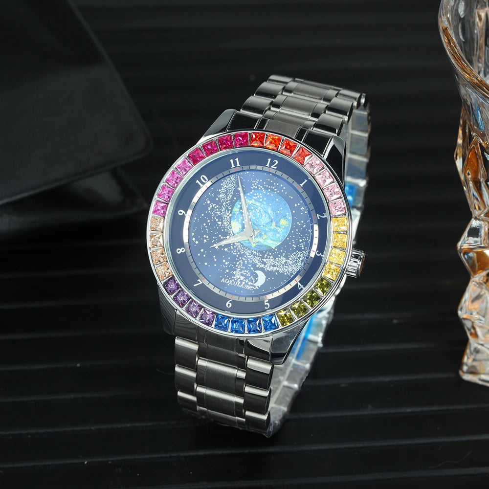 L'Orologio automatico uomo cielo stellato Design luminoso di PACOSHOP24.COM presenta una cassa argentata, un quadrante blu a tema cielo stellato e una lunetta con pietre preziose multicolori, visualizzate su una superficie nera strutturata accanto a un oggetto in vetro sfaccettato.