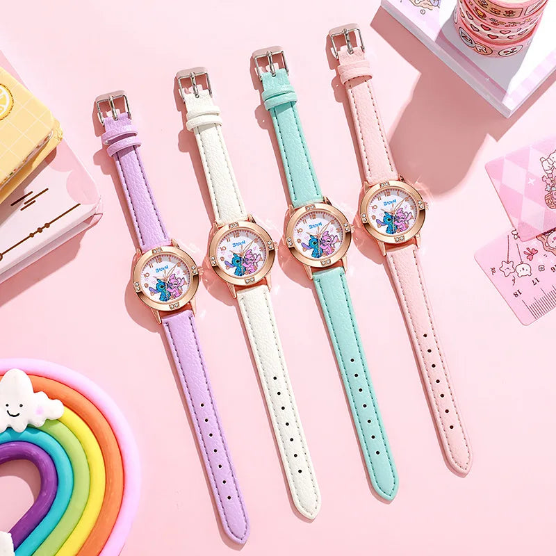 Quattro orologi pastello PACOSHOP24.COM Orologio bambini cartoon Stitch, con cinturini viola, bianchi, verde menta e rosa, sono allineati su una superficie rosa con simpatica cancelleria e un arcobaleno.
