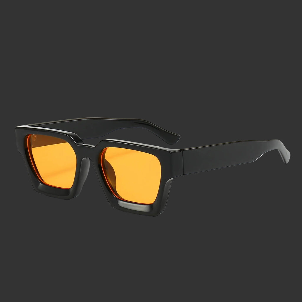 Un paio di Occhiali da sole con montatura quadrata Fashion Retrò Vintage di PACOSHOP24.COM, con montatura spessa nera e lenti UV400 color arancio, su sfondo grigio scuro.