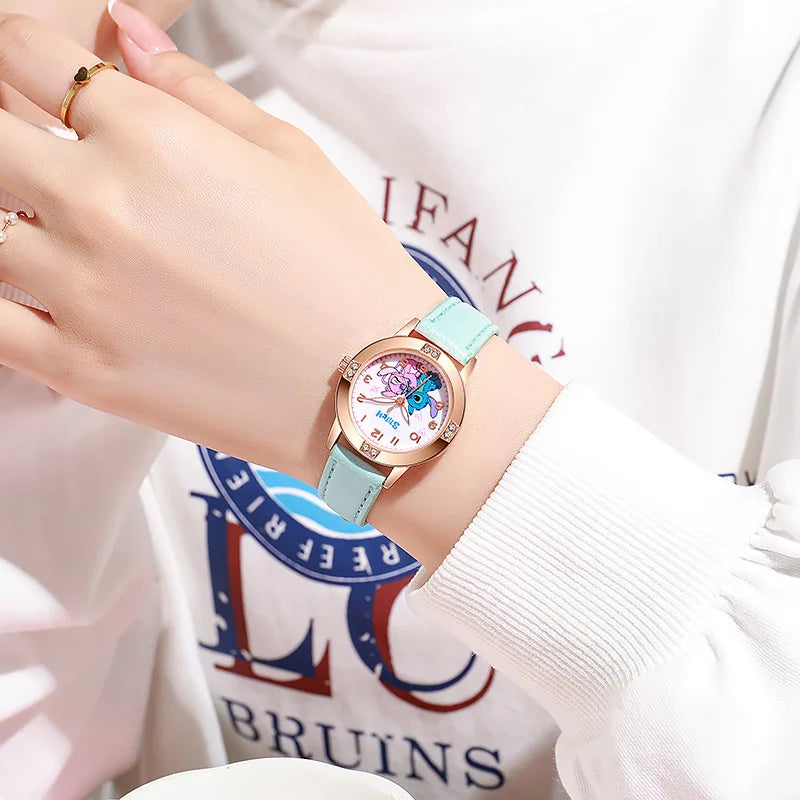 Una persona indossa un orologio azzurro PACOSHOP24.COM Orologio bambini cartoon Stitch, con quadrante rosa e bianco dal design decorativo, che si abbina perfettamente alla sua felpa bianca con scritte colorate.