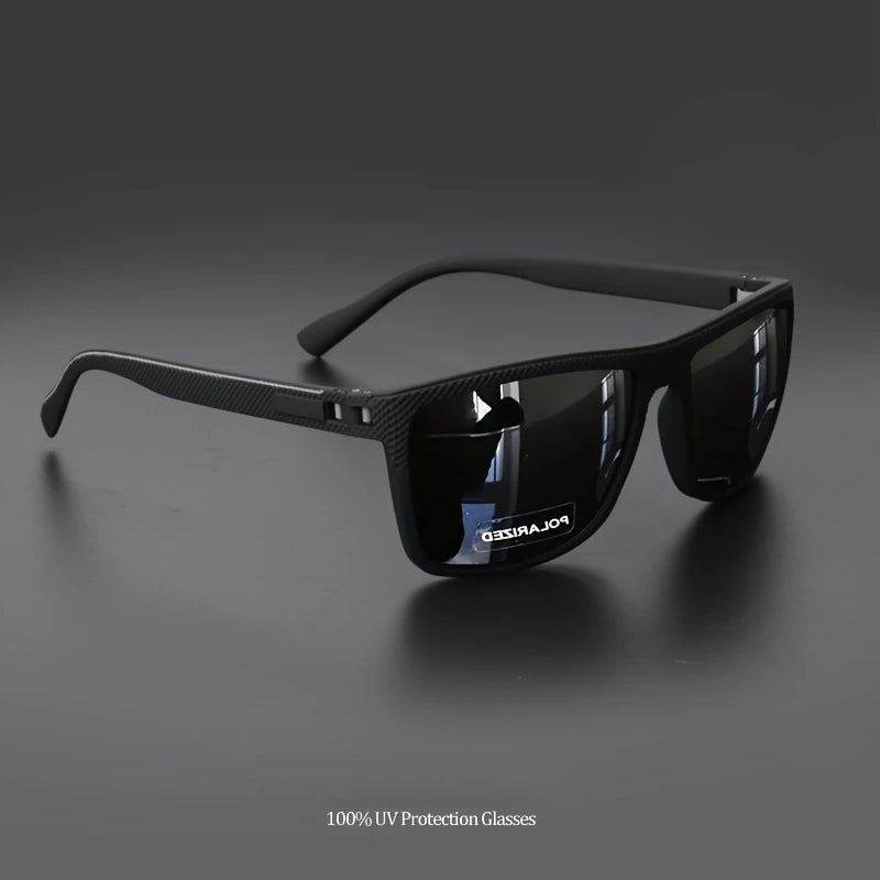 PACOSHOP24.COM Occhiali da sole unisex polarizzati a specchio sportivi con montatura spessa appoggiata su una superficie scura e riflettente. La lente destra riporta la scritta "POLARIZZATO" e il testo sottostante recita 100% Protezione UV Occhiali-lenti polarizzate UV400.