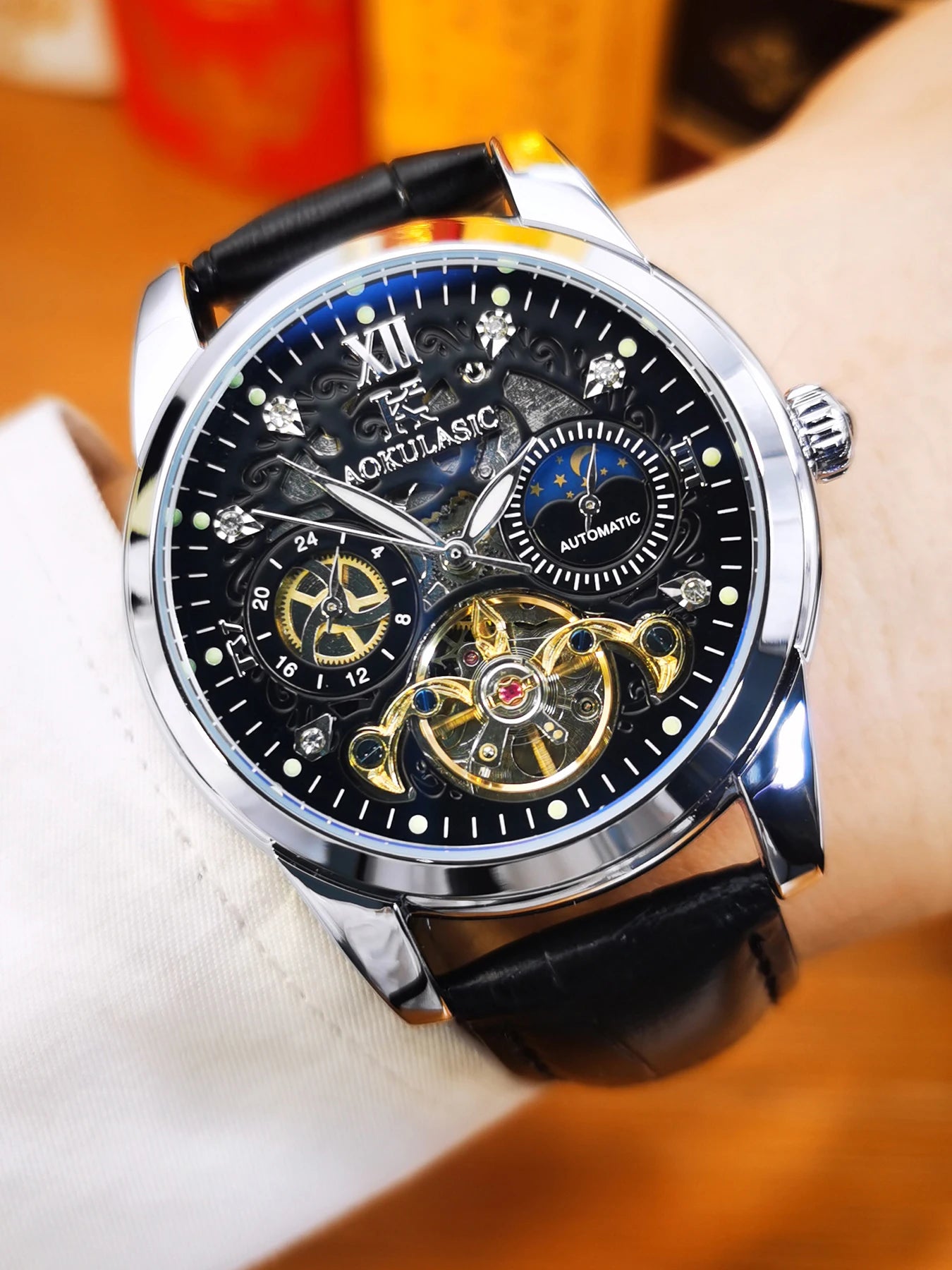 Un primo piano dell'Orologio automatico scheletrato uomo Tourbillon Design di PACOSHOP24.COM mostra il cinturino in pelle nera, la cassa argentata e l'intricato quadrante scheletrato con ingranaggi a vista, numeri romani e contatori multipli.