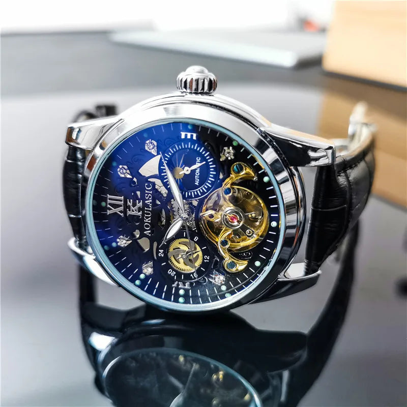 Primo piano dell'Orologio automatico scheletrato uomo Tourbillon Design di PACOSHOP24.COM con cinturino in pelle nera, quadrante blu, numeri romani e ingranaggi a vista, appoggiato su una superficie nera riflettente.
