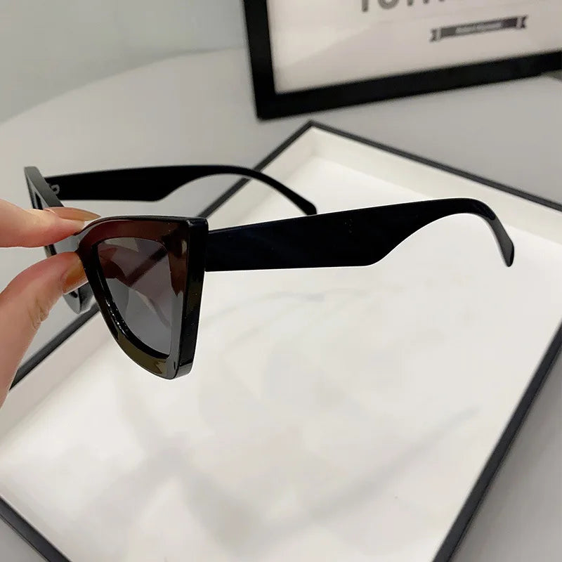 Una mano stringe PACOSHOP24.COM Occhiali da Sole Donna Occhi di Gatto - Fashion Style, presentati in un elegante astuccio.