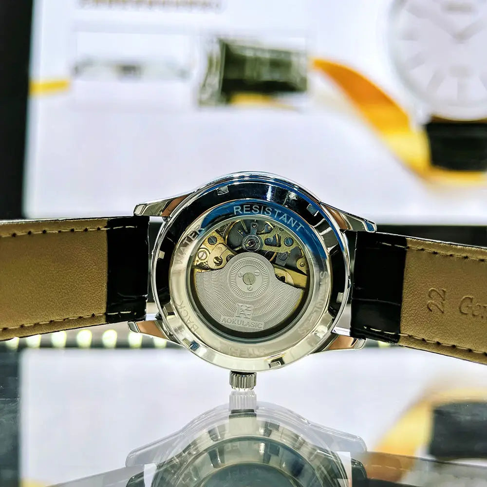 Un primo piano del fondello trasparente dell'Orologio automatico uomo cielo stellato Design luminoso di PACOSHOP24.COM rivela l'intricato movimento e il cinturino in vera pelle 22, mentre lo sfondo sfocato ne evidenzia la raffinata eleganza.