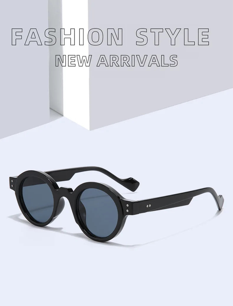 Gli Occhiali da Sole Rotondi punk Retrò UV400 - Uomo Donna di PACOSHOP24.COM, neri con montatura spessa, sono esposti su una superficie chiara. Il testo grigio in grassetto "FASHION STYLE NEW ARRIVALS" appare sullo sfondo per un'atmosfera moderna e minimalista.