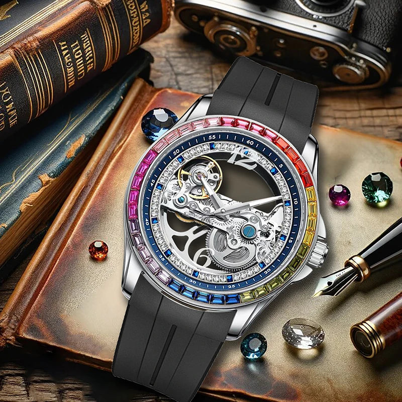 L'Orologio Automatico Skeleton Tourbillon Uomo di PACOSHOP24.COM, in elegante acciaio inox, con movimento meccanico a vista e lunetta multicolore, è esposto su un libro antico tra gemme colorate, una penna stilografica e una fotocamera vintage.