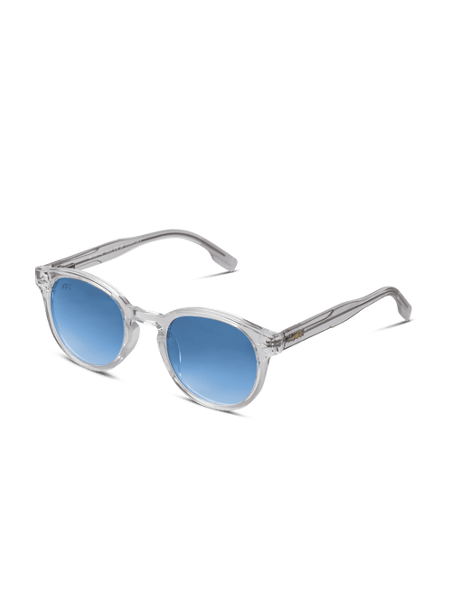 Luminatrix di X Frame Therapy è caratterizzato da montatura trasparente, lenti rotonde blu con protezione UV e stanghette trasparenti. Su sfondo bianco, questi occhiali da sole unisex offrono un look moderno ed elegante.