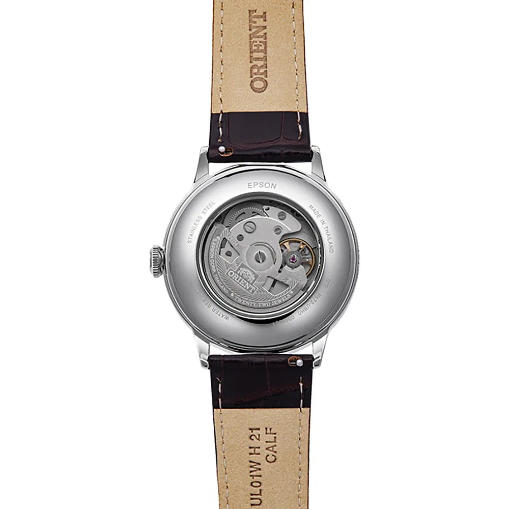 Un primo piano dell'Orient Bambino Automatico RA-AC0026R30B mostra il suo movimento automatico giapponese attraverso il fondello trasparente, abbinato a un cinturino in pelle marrone e al marchio Orient in evidenza.