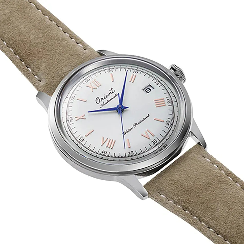 L'Orient Bambino Limited Edition 75th Anniversary RA-AC0027S30B, un orologio automatico da uomo color argento con quadrante bianco, lancette blu, numeri romani, datario e cinturino in pelle scamosciata beige di Orient, visualizzato ad angolo su sfondo bianco.