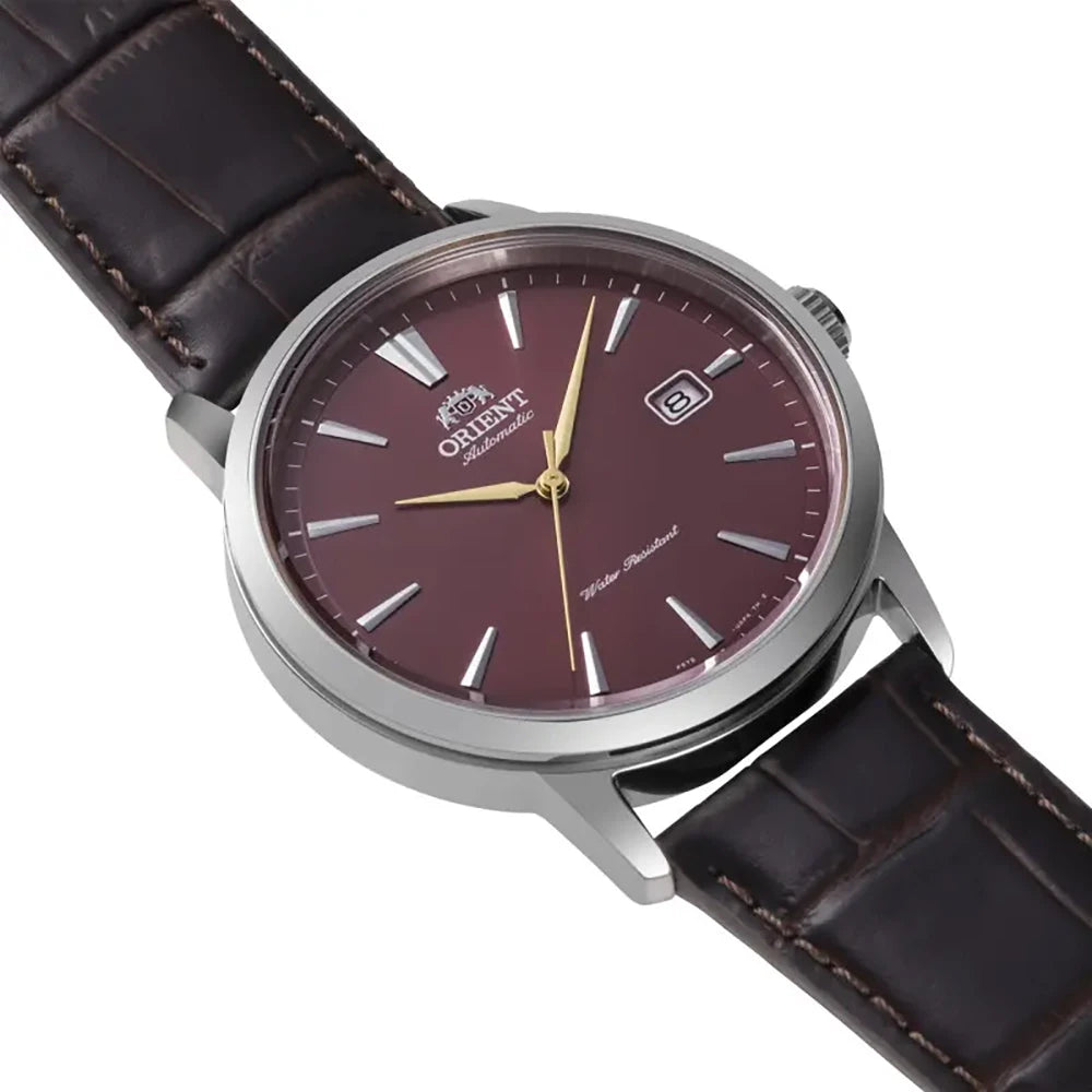 L'Orient Bambino RA-AC0F15R30B è un elegante orologio automatico uomo di Orient, caratterizzato da quadrante rosso, lancette e indici in oro, dati al 3, cinturino in pelle marrone e scritta "Automatic"/"Water Resistant" sul quadrante.