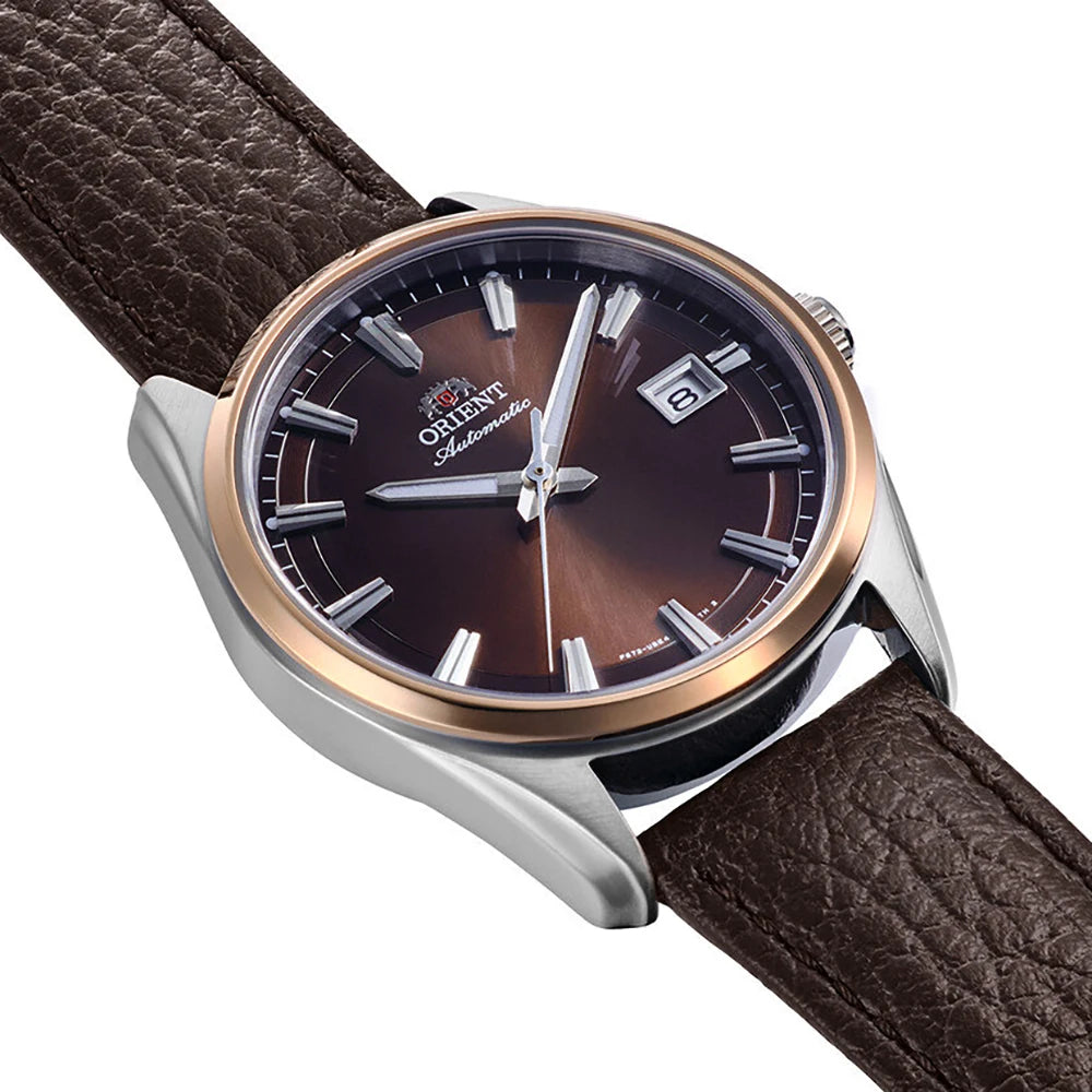 Primo piano dell'Orient Stretto Automatico RA-AC0R03Y30B, con cinturino in pelle marrone, quadrante marrone metallizzato, indici argentati, data al 3 e cassa argentata con lunetta in oro rosa: un classico orologio da uomo di Orient.