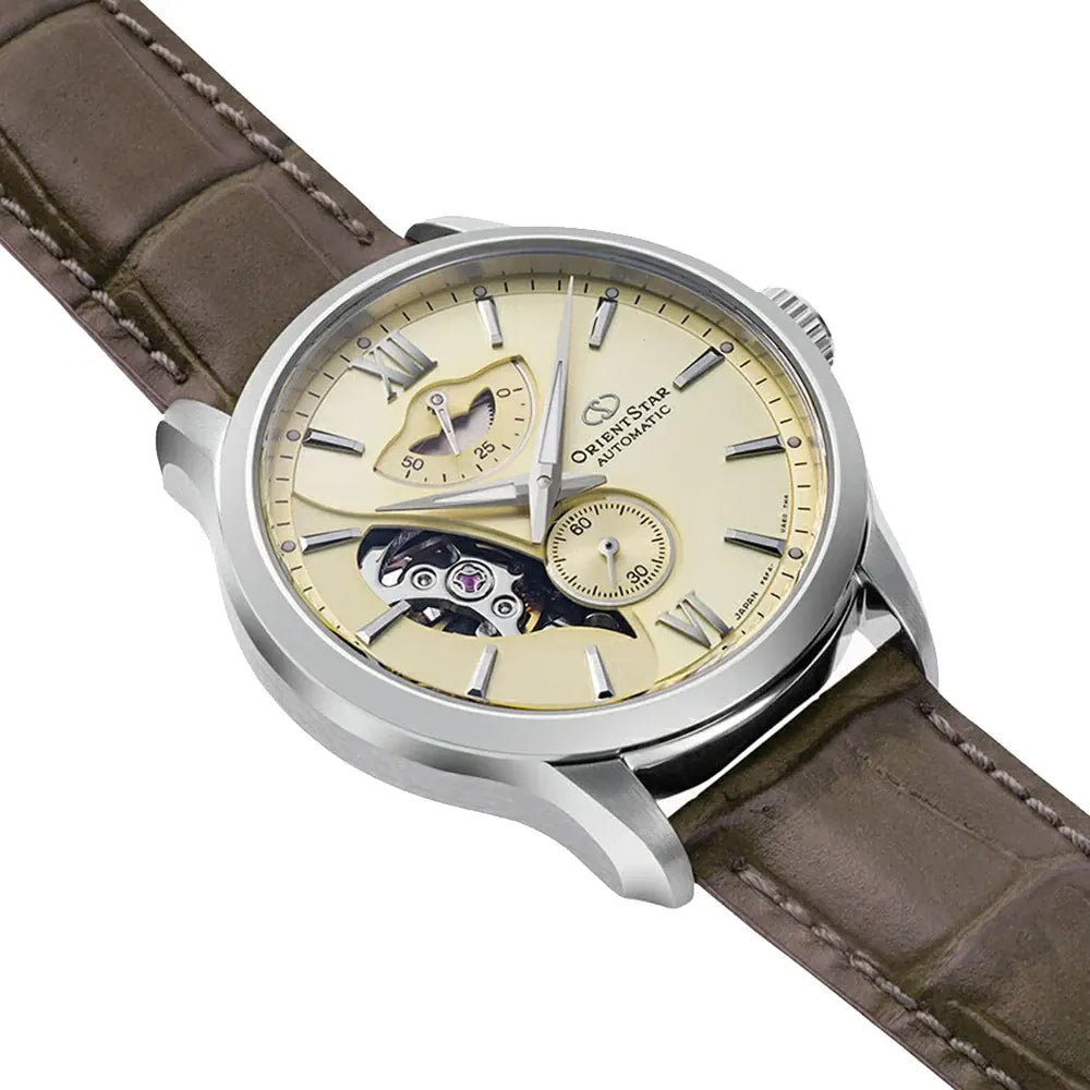 L'Orient Star Skeleton Automatico RE-AV0B10G00B di Orient è un orologio automatico da uomo con quadrante beige, indici argentati, due contatori, ingranaggio a vista, cinturino in pelle marrone e cassa in acciaio.